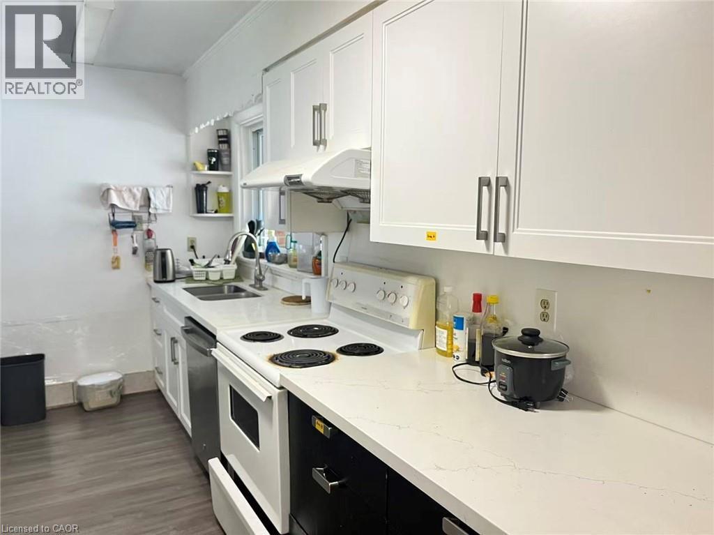 Kitchen featuring white shaker-style cabinetry with brushed nickel hardware, white stone-finish countertops, stainless steel sink, and wood-finish flooring - 110 Peppler Street, Waterloo, ON