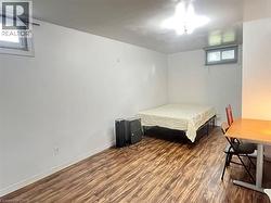 Room featuring wood-finish flooring, white painted walls, and a ceiling-mounted light fixture -