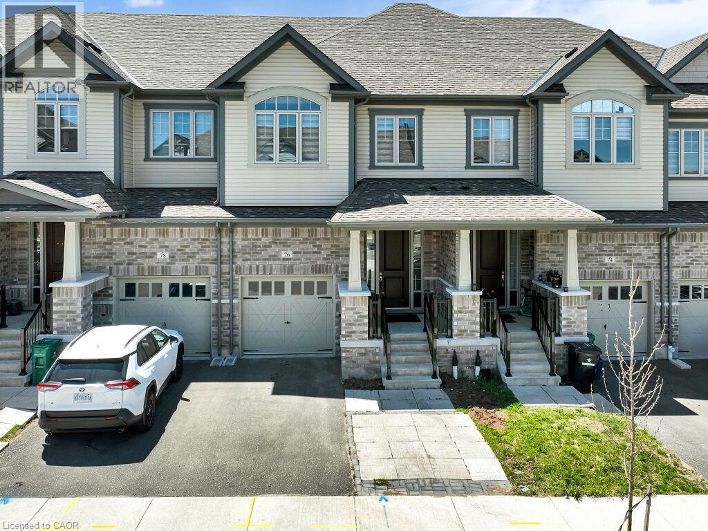 Townhome exterior featuring light-toned siding and a prominent brick facade - 76 Grassbourne Avenue, Kitchener, ON