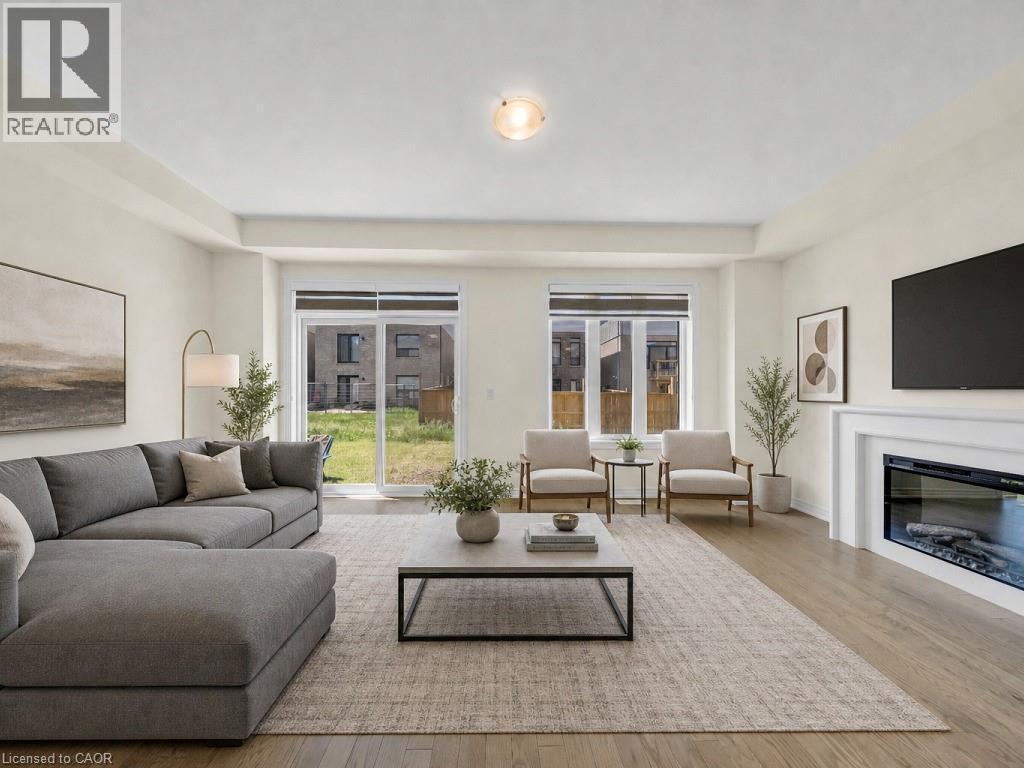 Bright living area featuring wood-finish flooring, a contemporary electric fireplace with a white mantel, and recessed lighting - 76 Grassbourne Avenue, Kitchener, ON