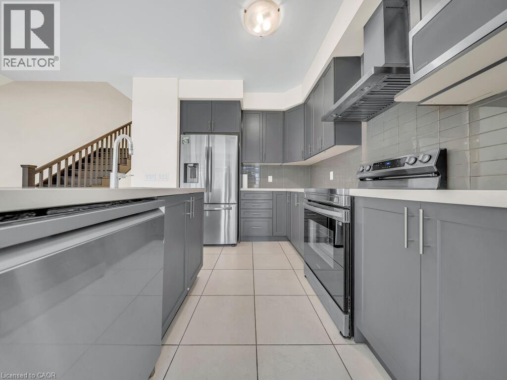 Modern kitchen featuring gray cabinetry, stainless steel appliances, and light tile flooring - 76 Grassbourne Avenue, Kitchener, ON