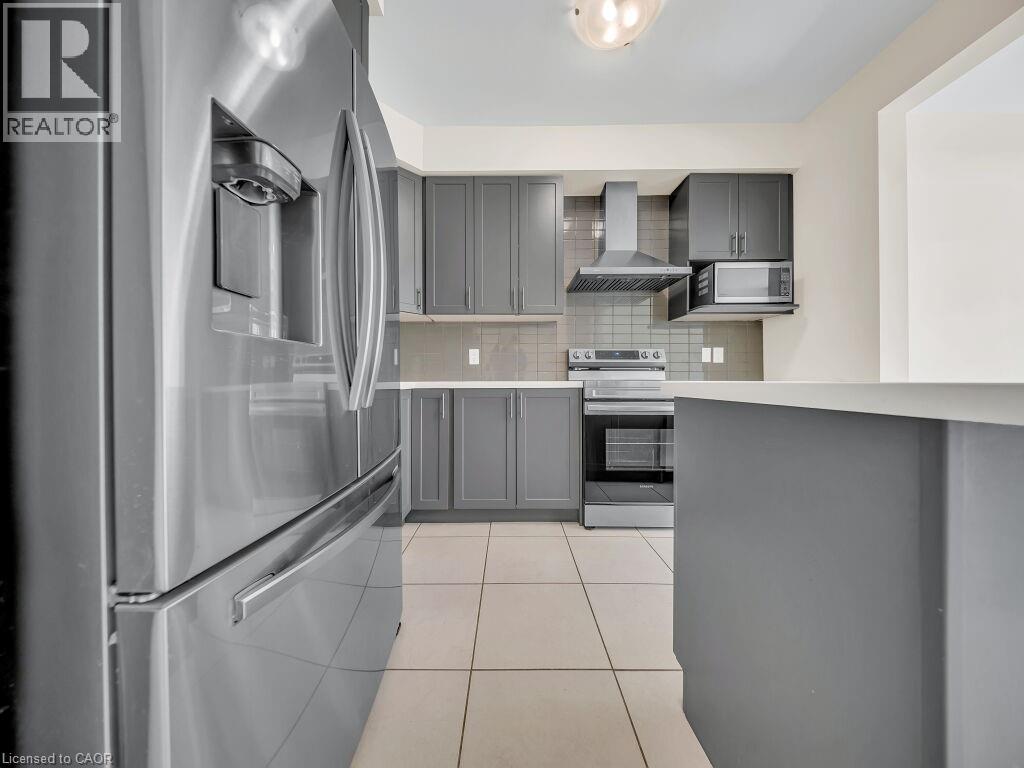 Contemporary kitchen featuring stainless steel appliances, grey cabinetry, and a tile backsplash - 76 Grassbourne Avenue, Kitchener, ON