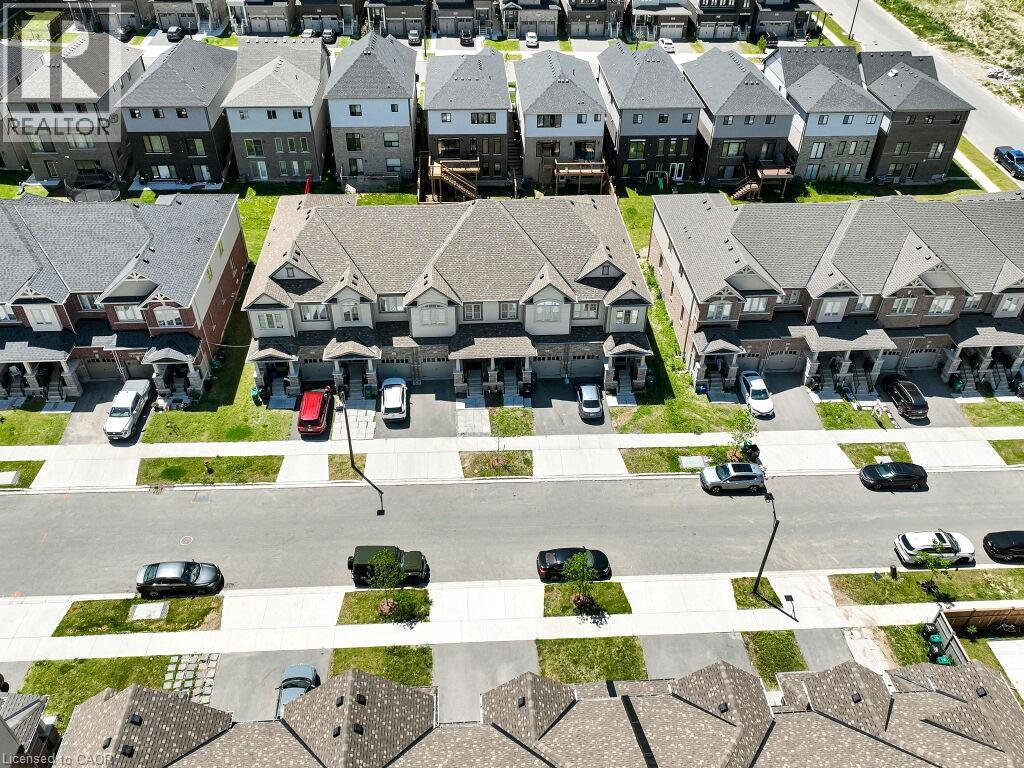 Contemporary townhome architecture featuring brick and siding exteriors, individual driveways, and manicured front lawns - 76 Grassbourne Avenue, Kitchener, ON