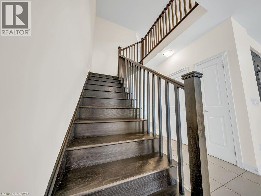 Dark wood-finish staircase featuring a square newel post and coordinating balusters - 76 Grassbourne Avenue, Kitchener, ON