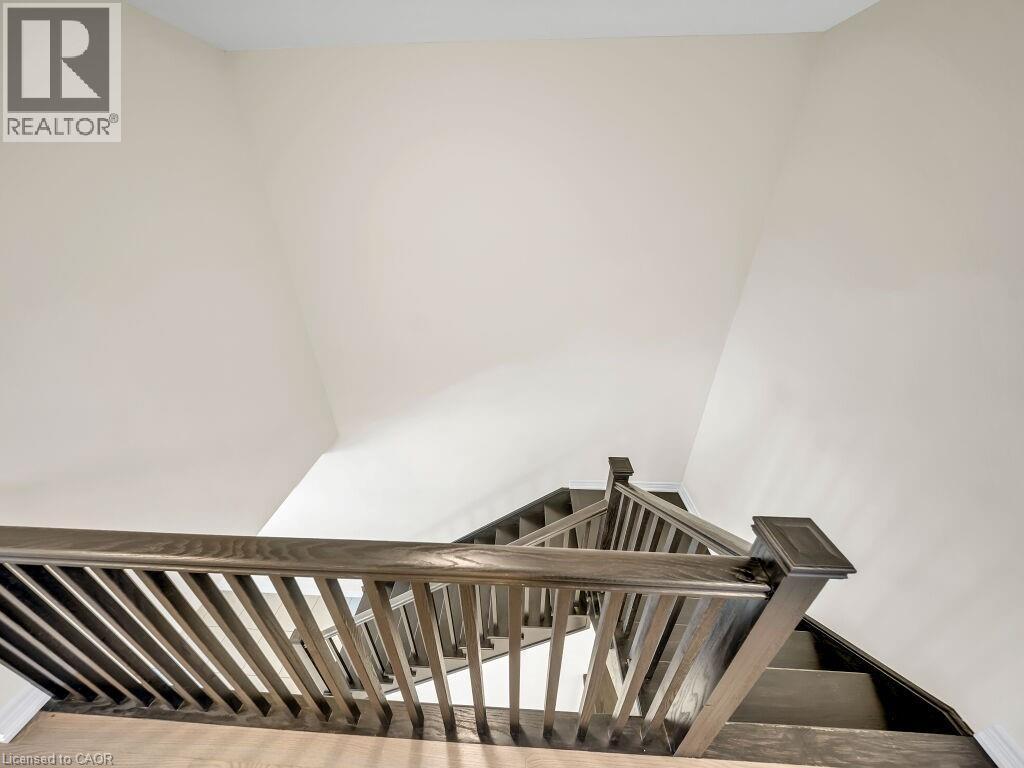 Staircase featuring dark wood-finish treads and risers, coordinating balusters, and a substantial handrail - 76 Grassbourne Avenue, Kitchener, ON