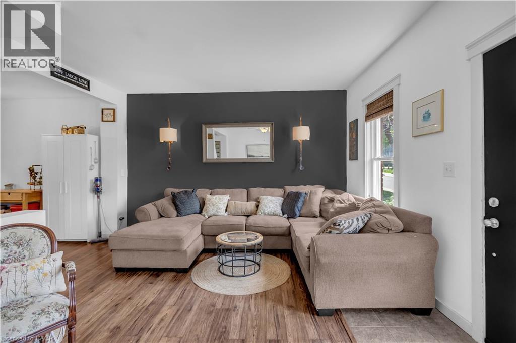 Living area featuring wood-finish flooring, a dark accent wall, and decorative sconce lighting - 30 Sunset Avenue, Hamilton, ON