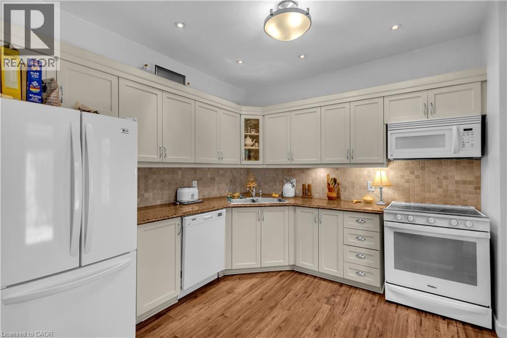 Corner kitchen featuring wood-finish flooring, light-toned cabinetry, and granite-look countertops - 30 Sunset Avenue, Hamilton, ON