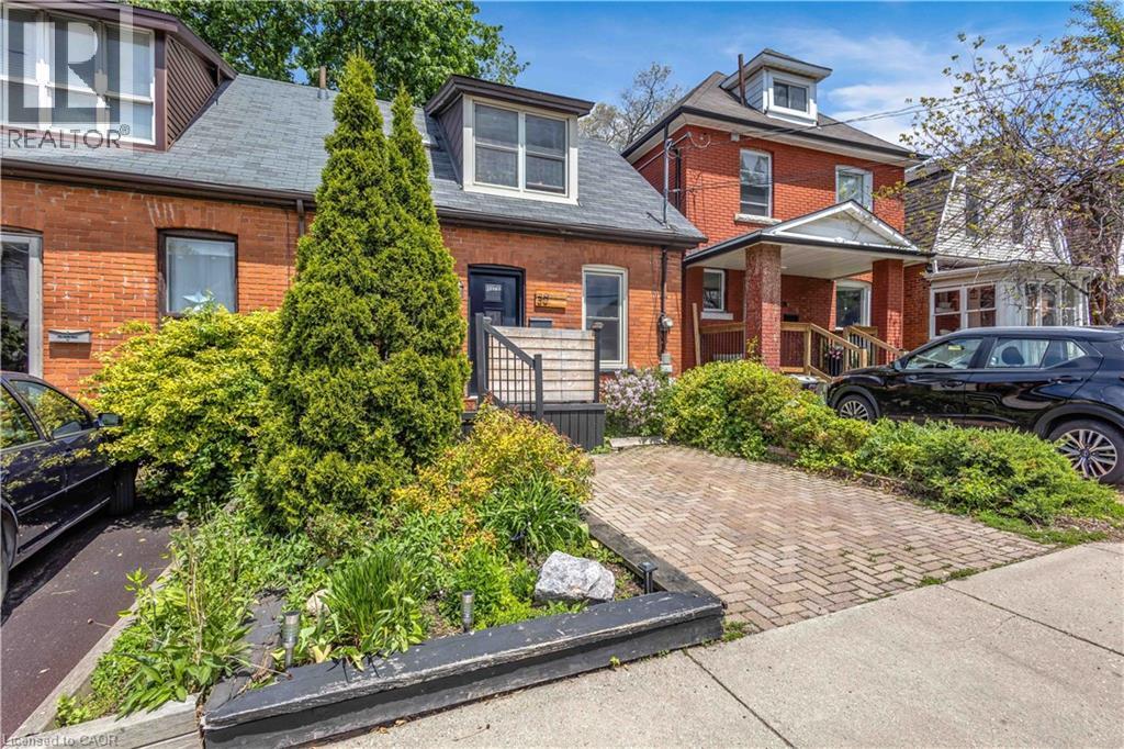 Brick facade residence featuring a front dormer window, dark shingles, and a paved driveway - 30 Sunset Avenue, Hamilton, ON