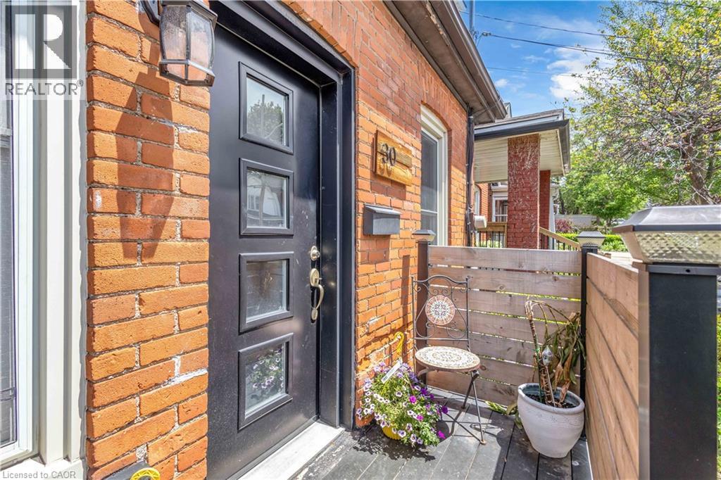 Brick exterior with a contemporary black entry door featuring multiple glass panes - 30 Sunset Avenue, Hamilton, ON