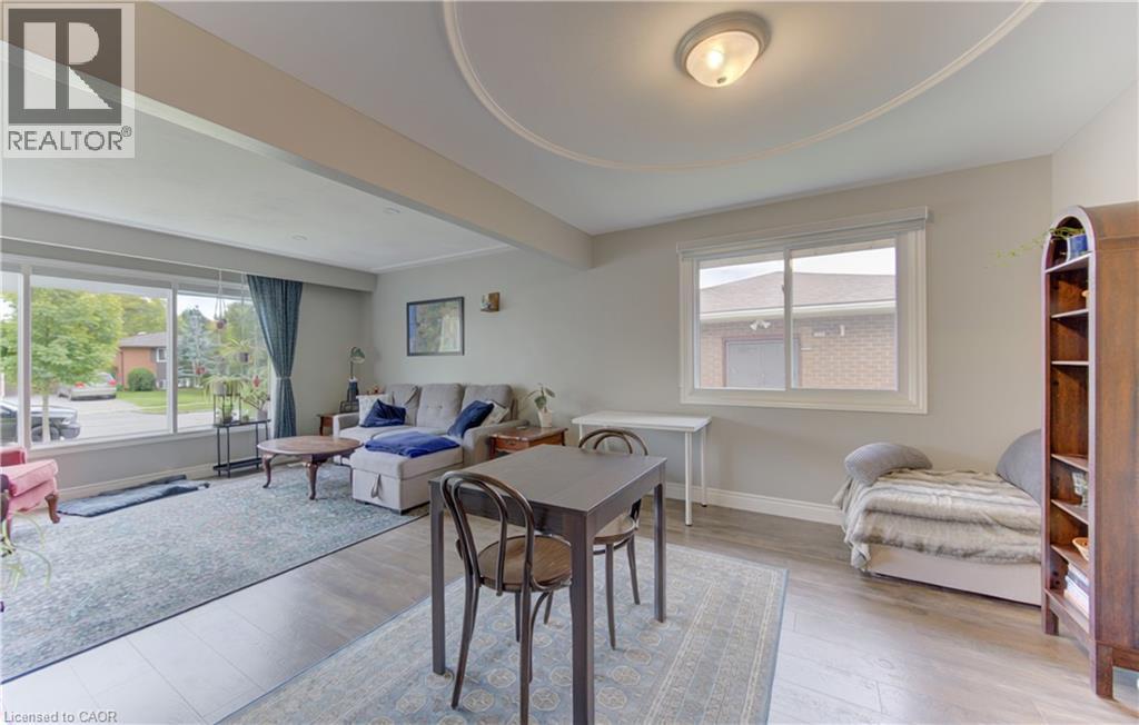 Spacious living area featuring large picture windows, wood-finish flooring, and a decorative ceiling medallion with an attached flush-mount light fixture - 127 Strathcona Crescent, Kitchener, ON