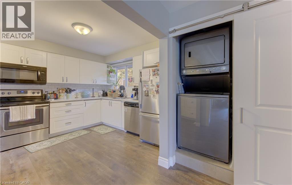 Kitchen featuring white cabinetry, stainless steel appliances, white subway tile backsplash, and wood-finish flooring - 127 Strathcona Crescent, Kitchener, ON