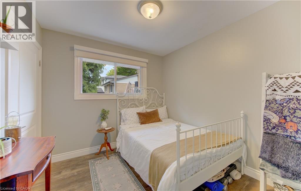 Bright room featuring a window with white trim, wood-finish flooring, light neutral wall paint, and white baseboards - 127 Strathcona Crescent, Kitchener, ON