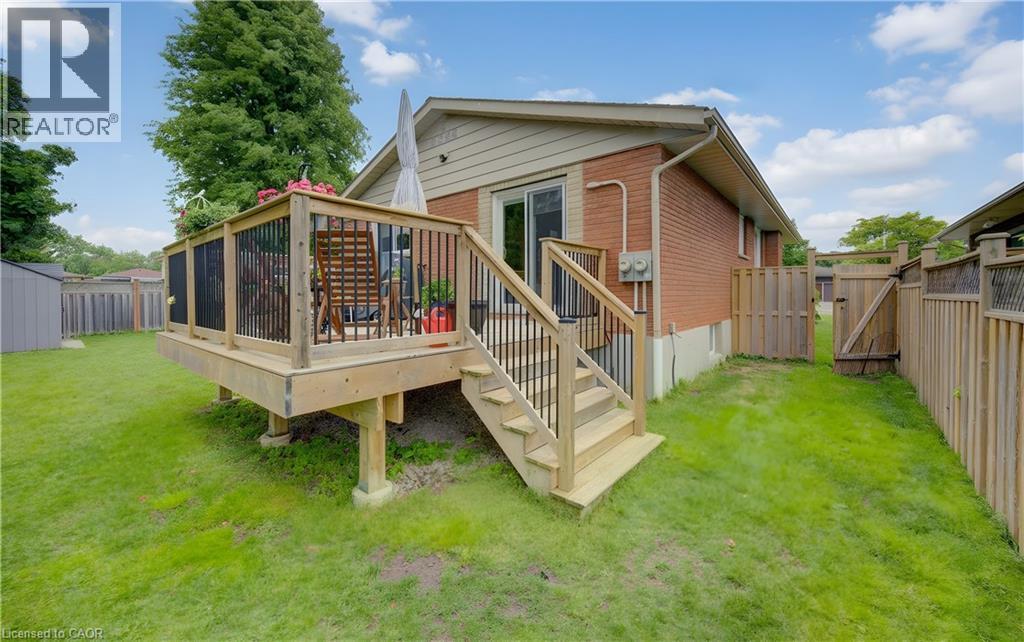Elevated wooden deck with black balusters and a staircase leading to a manicured lawn - 127 Strathcona Crescent, Kitchener, ON
