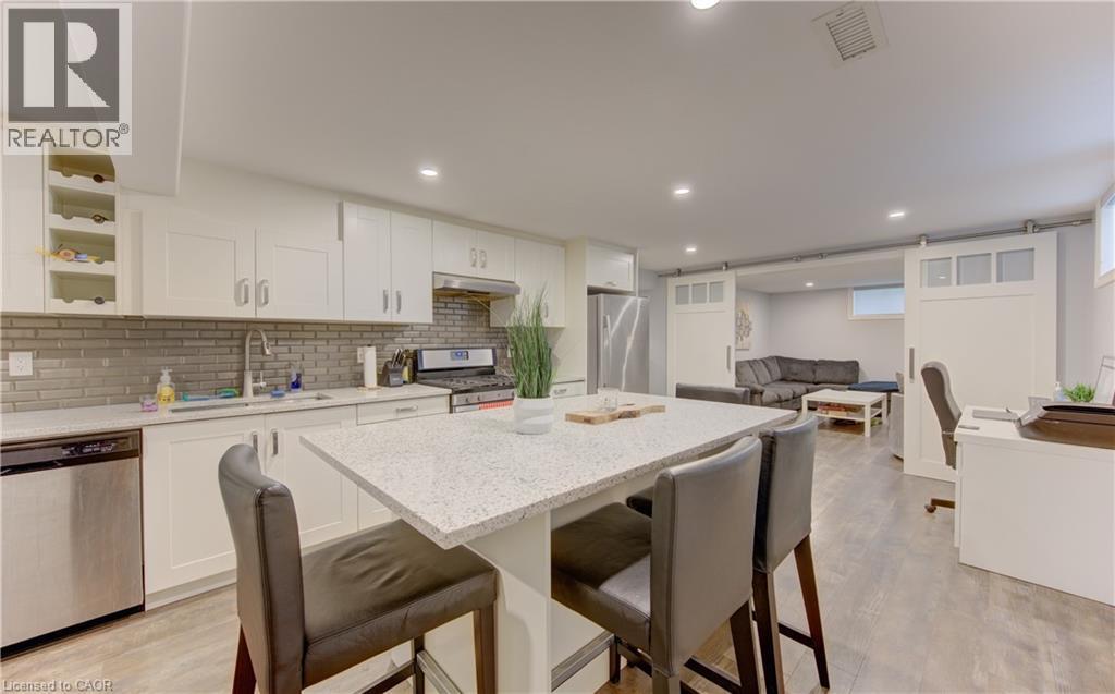 Kitchen with white cabinetry, stainless steel appliances, and a tiled backsplash - 127 Strathcona Crescent, Kitchener, ON
