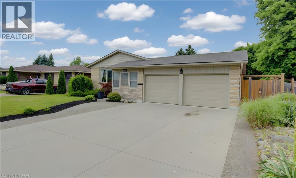 Stone and siding exterior with a two-car garage, concrete driveway, and established front landscaping - 127 Strathcona Crescent, Kitchener, ON