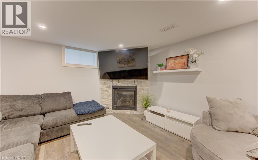 Corner fireplace featuring a stacked stone surround and recessed lighting - 127 Strathcona Crescent, Kitchener, ON