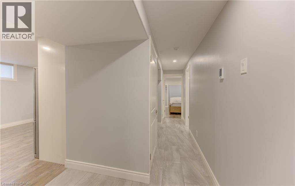Hallway featuring light wood-finish flooring, light grey walls, white trim, and recessed lighting - 127 Strathcona Crescent, Kitchener, ON