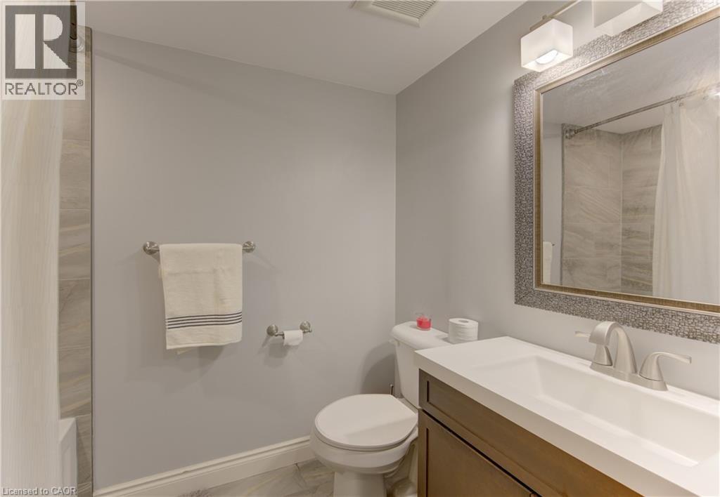 Bathroom featuring a vanity with a white countertop and undermount sink, brushed nickel faucet, large mirror with a textured frame, and light gray wall paint - 127 Strathcona Crescent, Kitchener, ON