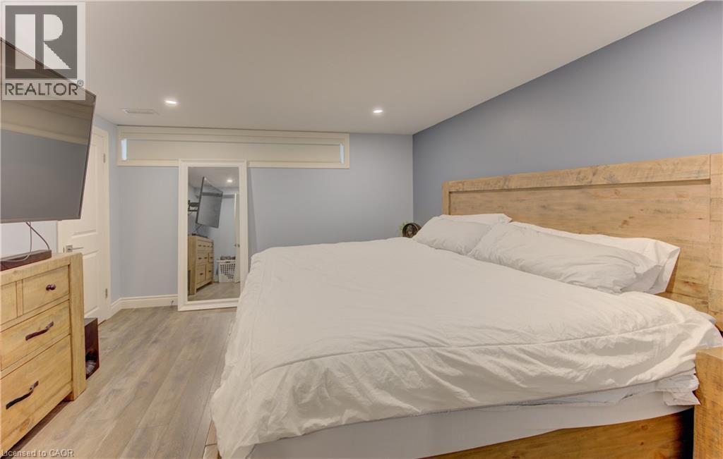 Bedroom featuring light-tone wood-finish flooring, recessed lighting, and a window with a roller blind - 127 Strathcona Crescent, Kitchener, ON