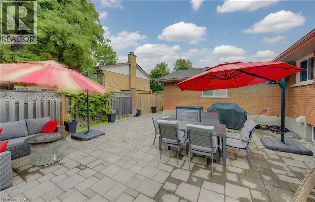 Expansive backyard patio featuring paver stones, a stone-clad fire pit, and mature perimeter trees - 127 Strathcona Crescent, Kitchener, ON