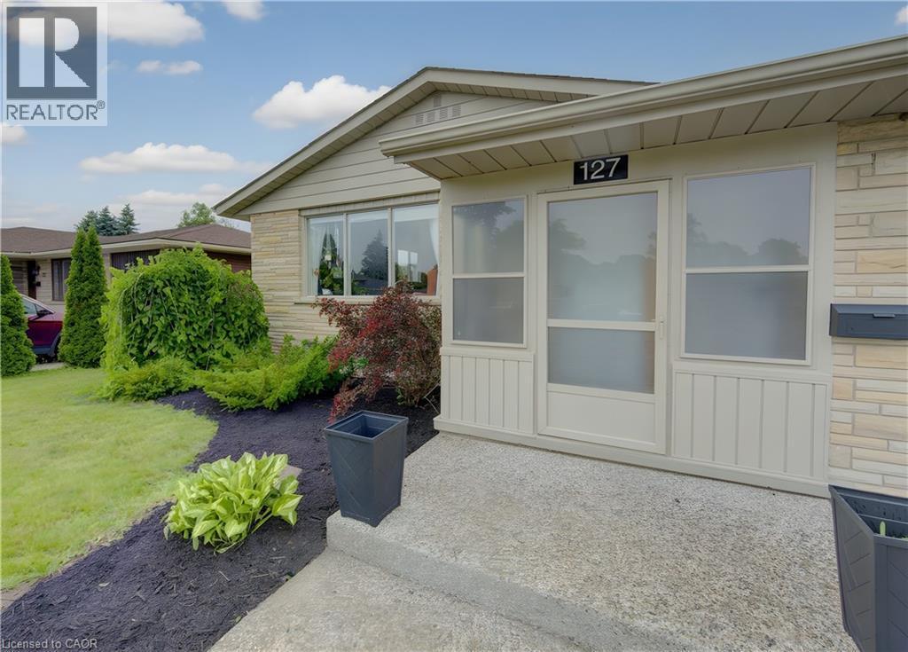 Brick veneer exterior featuring a covered entry, established landscaping, and a concrete pathway - 127 Strathcona Crescent, Kitchener, ON