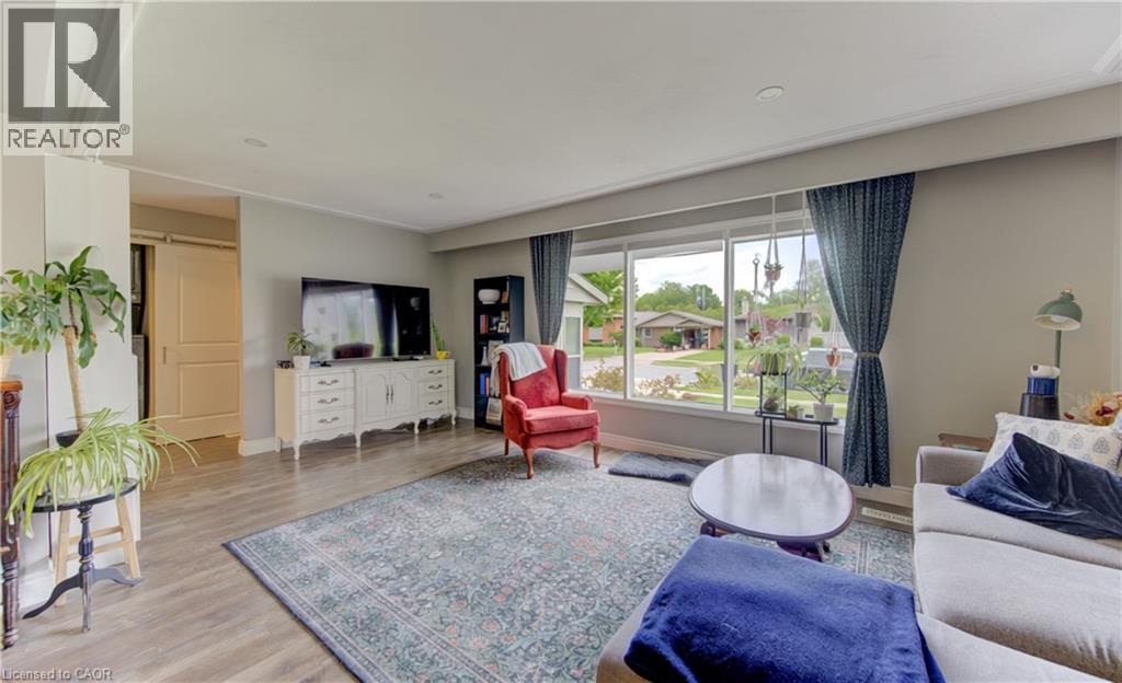 Spacious living area featuring wood-finish flooring, a large picture window, recessed lighting, and a barn door entry - 127 Strathcona Crescent, Kitchener, ON