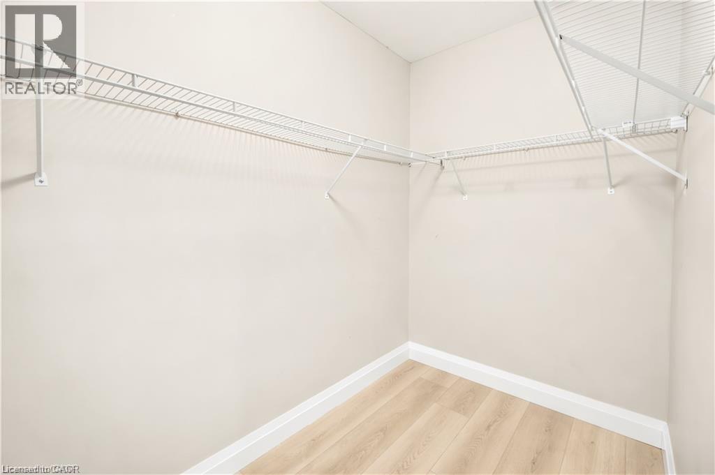 Walk-in closet featuring light wood-finish flooring, white baseboards, and wire shelving on multiple walls - 129 St George Street, Kitchener, ON