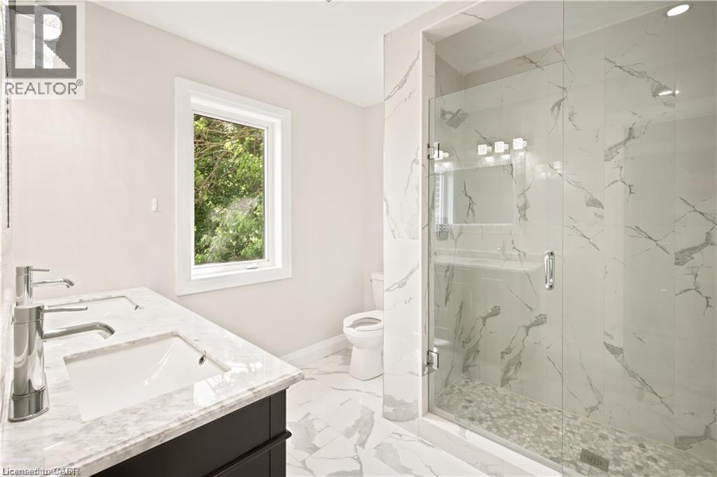 Contemporary bathroom featuring a spacious glass-enclosed shower with pebble flooring and large-format wall tiles - 129 St George Street, Kitchener, ON