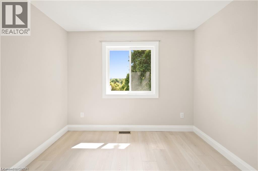 Room featuring a single window, light-toned walls, white baseboards, and wood-finish flooring - 129 St George Street, Kitchener, ON