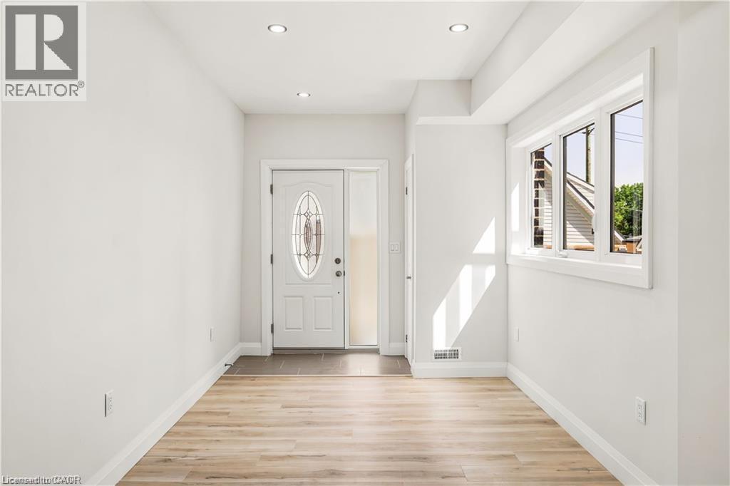 Entryway featuring a decorative glass front door, side-light, recessed lighting, wood-finish flooring, and a large window - 129 St George Street, Kitchener, ON