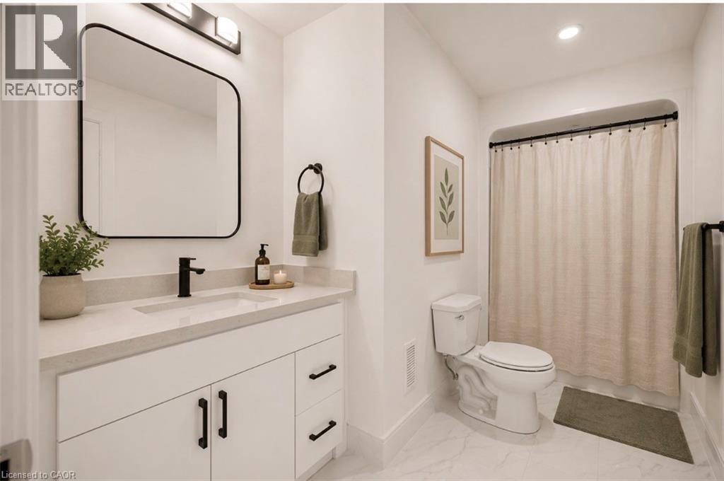 Modern bathroom featuring a white vanity with black hardware, a light-toned countertop, and a rectangular undermount sink - 129 St George Street, Kitchener, ON