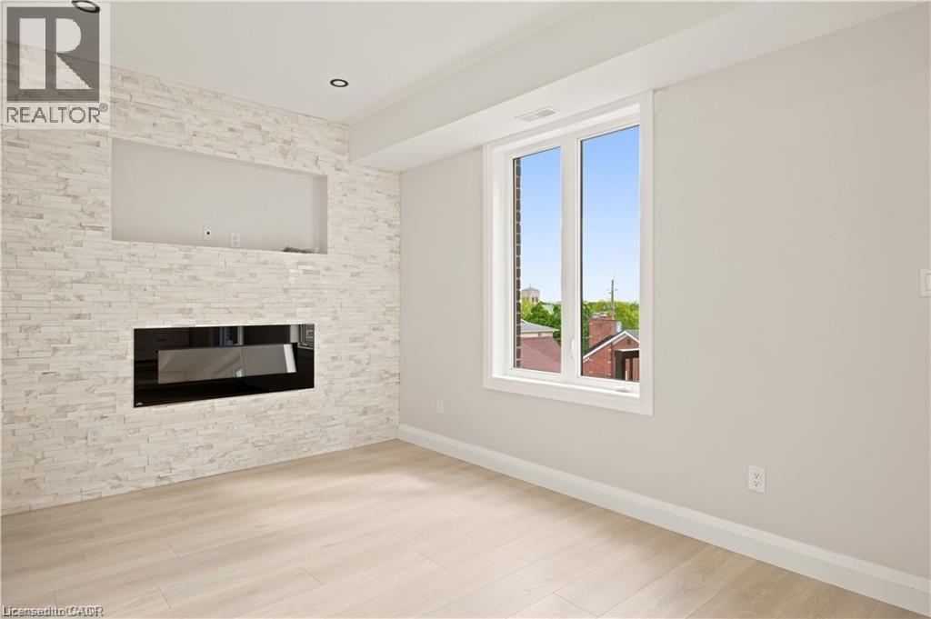 Living space featuring a stacked stone accent wall with an integrated linear electric fireplace and built-in media niche - 129 St George Street, Kitchener, ON