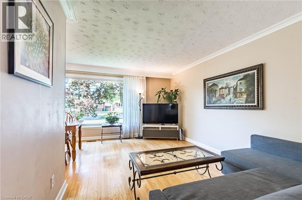Spacious living area featuring light wood-finish flooring, a large picture window, crown molding, and neutral wall tones - 1293 Daimler Road, Mississauga, ON - Indoor Photo Showing Living Room