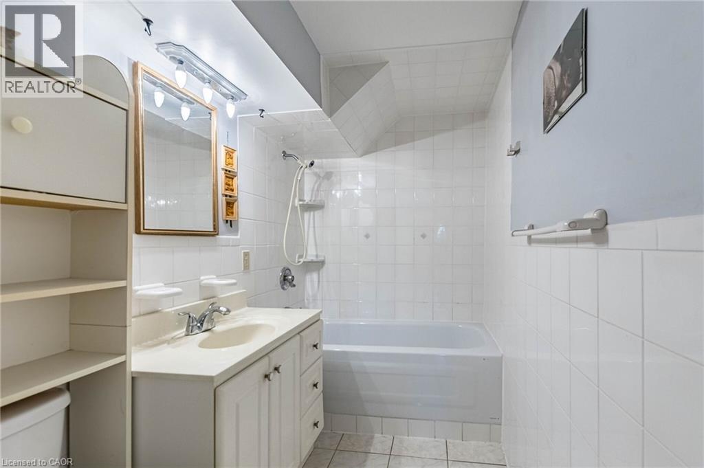 Bathroom featuring white tile walls, a built-in bathtub, and a vanity with a drop-in sink - 1293 Daimler Road, Mississauga, ON - Indoor Photo Showing Bathroom