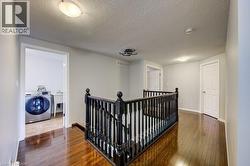 Hardwood flooring throughout the upper hallway with a dark wood balustrade -