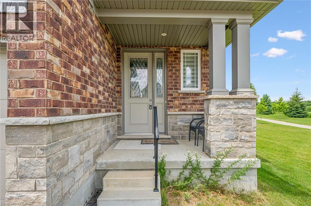 Brick exterior with stone accents, a covered front porch, and a light-colored entry door with decorative glass - 153 Rivertrail Avenue, Kitchener, ON - Outdoor