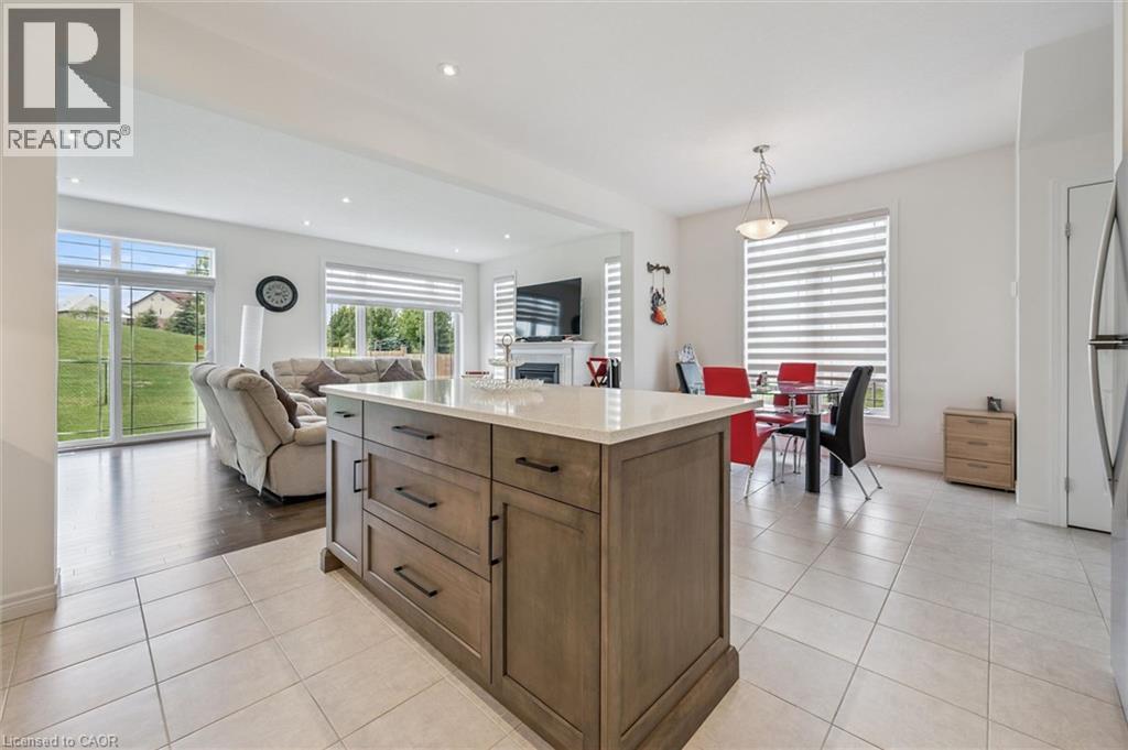 Kitchen island featuring a light-toned countertop, wood-finish cabinetry, and dark hardware - 153 Rivertrail Avenue, Kitchener, ON - Indoor