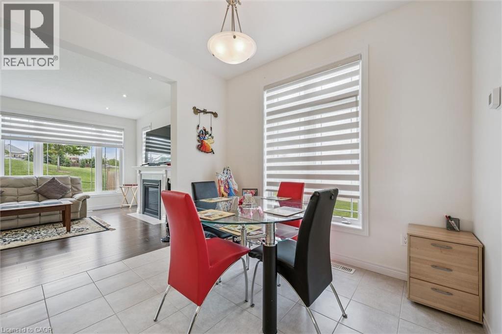 Dining area featuring light-toned tile flooring, a contemporary ceiling light fixture, and a large window with horizontal blinds - 153 Rivertrail Avenue, Kitchener, ON - Indoor