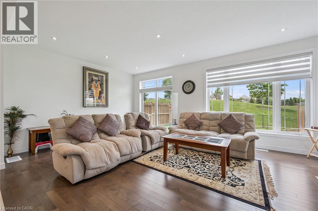 Spacious living area featuring large windows with horizontal blinds, recessed ceiling lighting, and dark wood-finish flooring - 153 Rivertrail Avenue, Kitchener, ON - Indoor Photo Showing Living Room