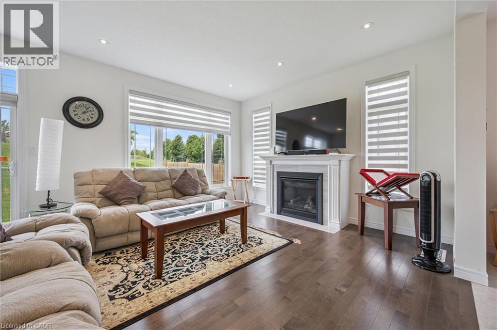 Living area featuring wood-finish flooring, a white mantel fireplace, recessed lighting, and large windows with horizontal blinds - 153 Rivertrail Avenue, Kitchener, ON - Indoor Photo Showing Living Room With Fireplace
