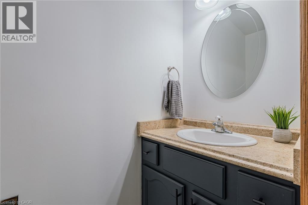 Bathroom vanity featuring a light-colored countertop, integrated white sink, and dark cabinetry with black pulls - 141 Lynndale Road, Simcoe, ON