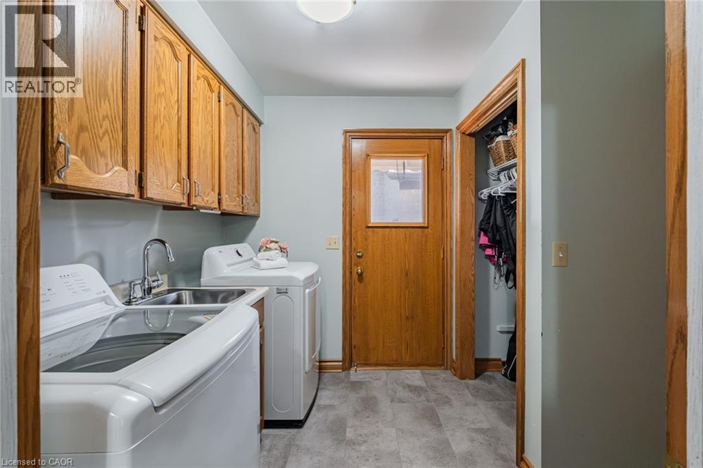 Dedicated laundry area featuring a utility sink, wood-finish cabinetry, and resilient flooring - 141 Lynndale Road, Simcoe, ON