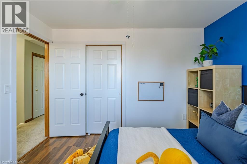 Bedroom featuring wood-finish flooring, white paneled doors, and a partial accent wall - 141 Lynndale Road, Simcoe, ON