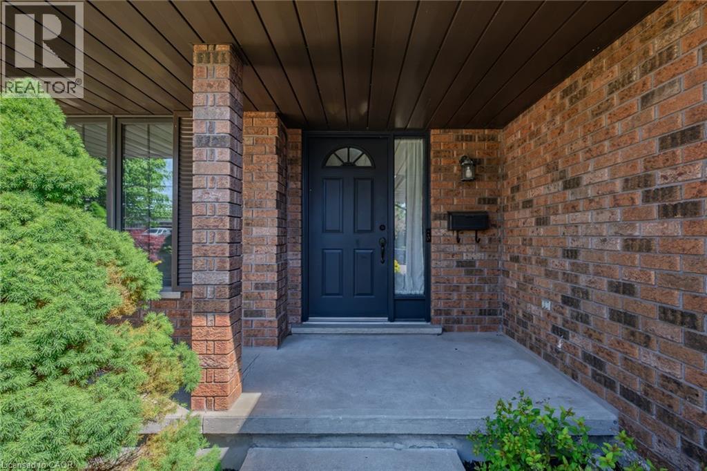 Brick exterior featuring a dark entry door with arched lites, a transom window, and a side lite - 141 Lynndale Road, Simcoe, ON
