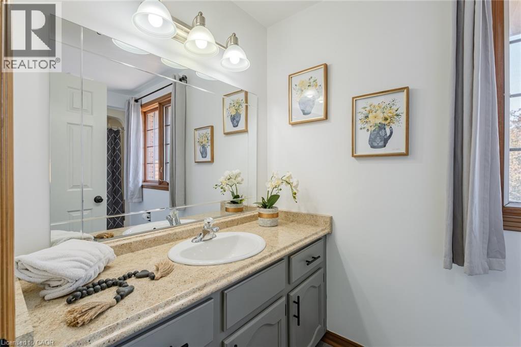 Bathroom featuring a single vanity with an integrated sink, a light-toned countertop, and gray cabinetry with dark hardware - 141 Lynndale Road, Simcoe, ON