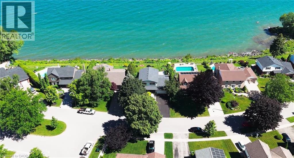 Waterfront property featuring a private swimming pool, expansive green lawn, mature trees, and a paved driveway - 15 Cheval Drive, Grimsby, ON - Outdoor With Body Of Water With View