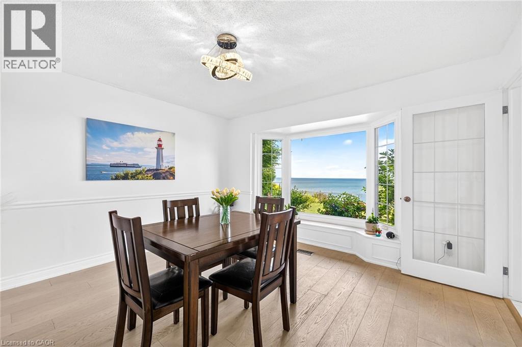 Dining area featuring a prominent bay window with water scenery - 15 Cheval Drive, Grimsby, ON - Indoor Photo Showing Dining Room
