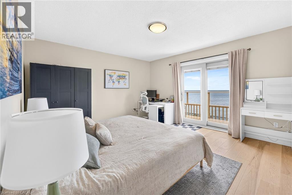 Sliding glass doors opening to a private balcony overlooking the water - 15 Cheval Drive, Grimsby, ON - Indoor Photo Showing Bedroom
