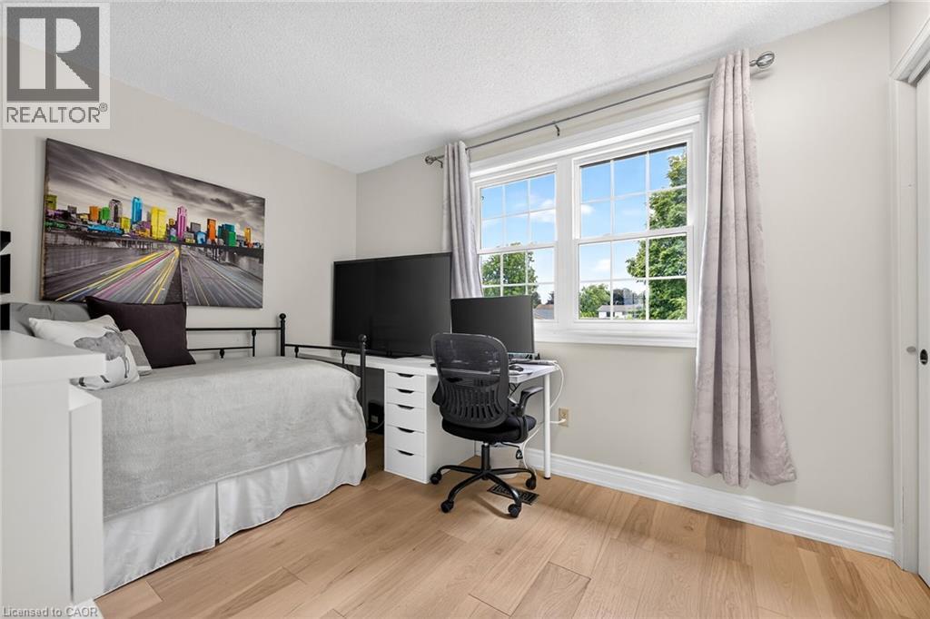 Spacious room featuring light wood-finish flooring, a large multi-pane window, and neutral wall tones - 15 Cheval Drive, Grimsby, ON - Indoor
