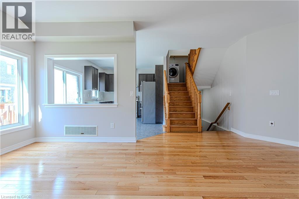 Open concept living space featuring wood-finish flooring, light grey wall paint, and a pass-through window to the kitchen - 3896 Tufgar Crescent, Burlington, ON